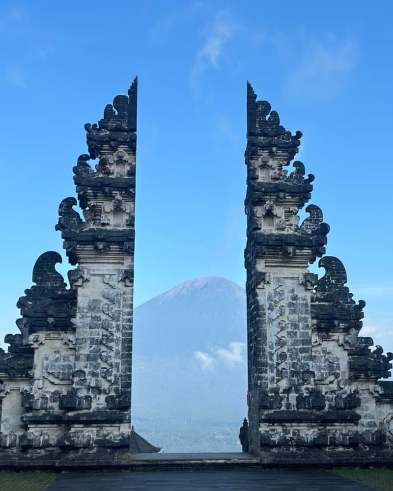 Carved split gate of Lempuyang Temple framing Mount Agung under a blue sky
